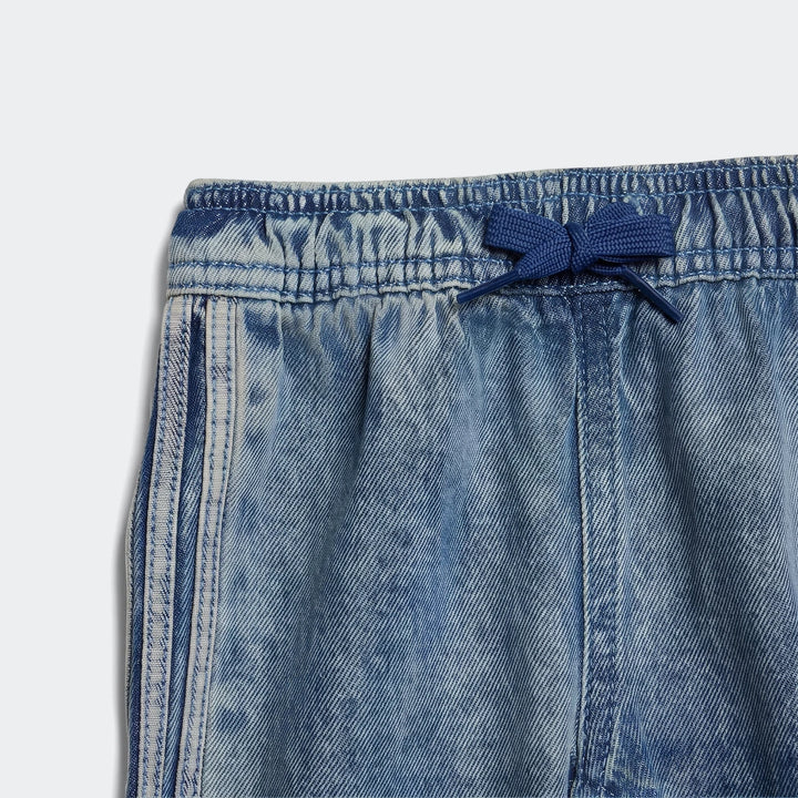 Close-up of blue Firebird denim track pants featuring an elastic waistband with a blue drawstring tied in a bow and white
