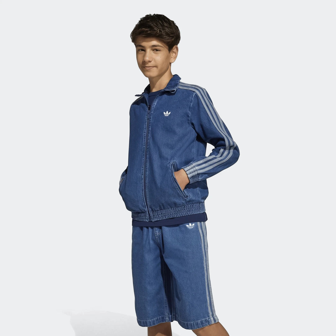 Young boy wearing an Adidas Firebird denim track suit, featuring a zip-up jacket and matching shorts with signature stripes.