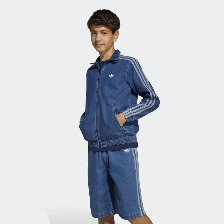 Young boy wearing an Adidas Firebird denim track suit, featuring a zip-up jacket and matching shorts with signature stripes.