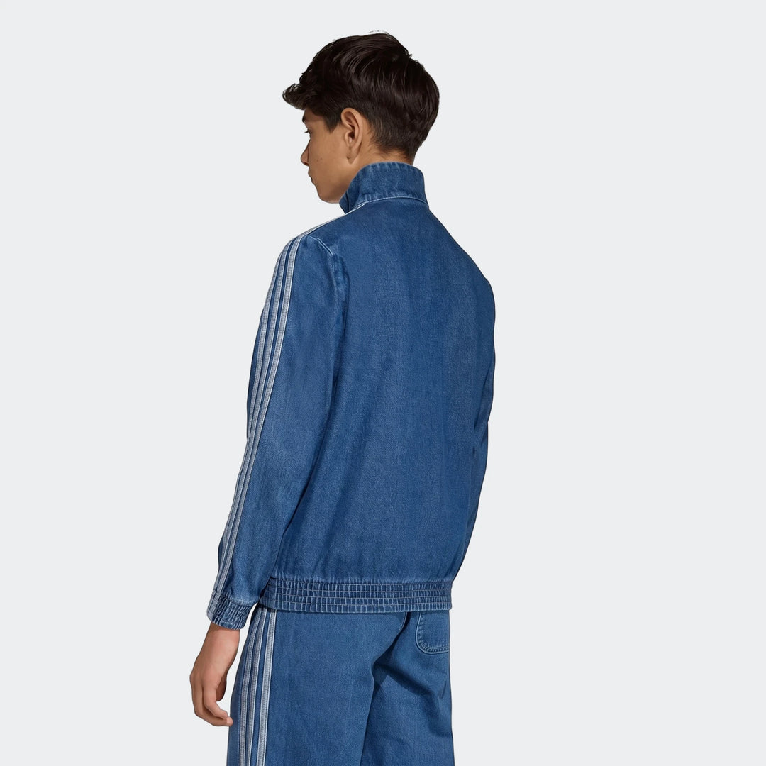 Young man models a blue denim Firebird Track Top and matching pants, featuring classic white stripe detailing, viewed from