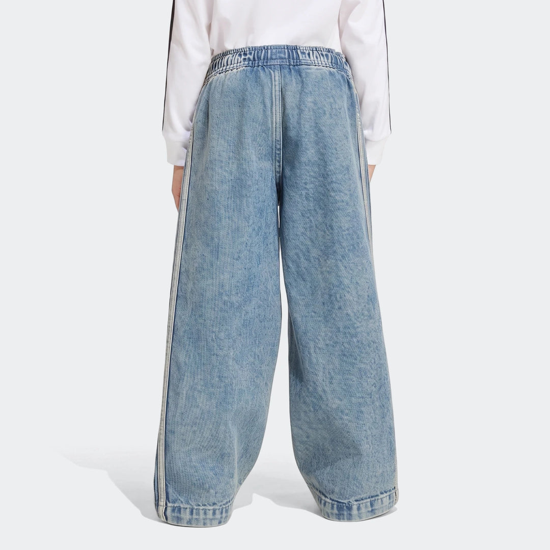 Firebird Loose Denim Track Pants in a light wash blue, featuring wide legs and white side stripes, worn by a model from