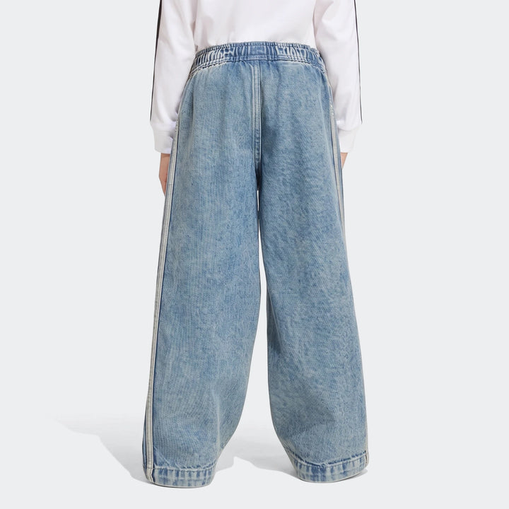 Firebird Loose Denim Track Pants in a light wash blue, featuring wide legs and white side stripes, worn by a model from