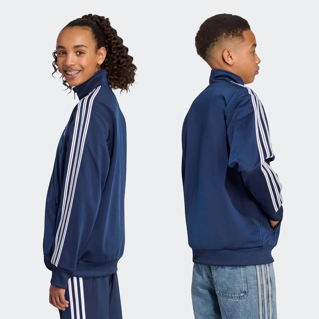Two young models wearing navy blue Firebird Loose Reversible Tracktops with white stripes, shown from mid-torso up.