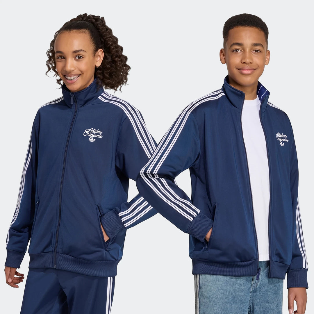 Two young models wearing navy blue Adidas Firebird Loose Reversible Tracktops with white stripes.