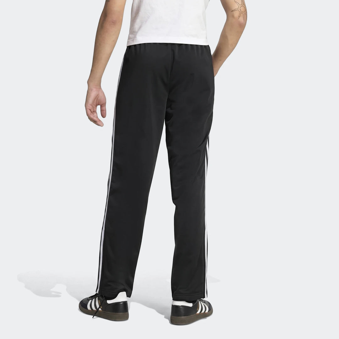Black Firebird Track Pants with white side stripes worn by a male model, captured from the back view.