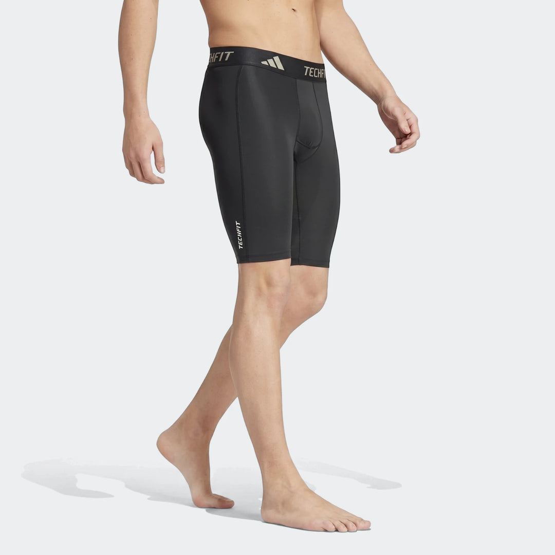 Black Adidas Techfit compression football base layer short tights on male model, side view.