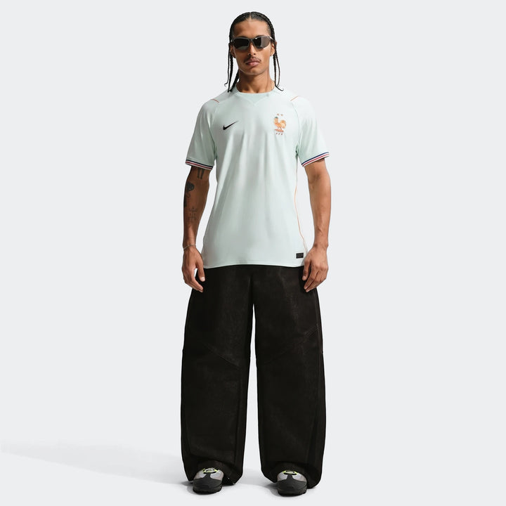 Male model wearing a France National Team 2026 Stadium Away Green Nike Dri-Fit soccer jersey, black pants, and sneakers.