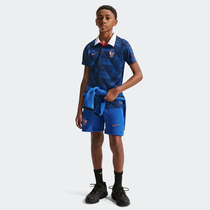 Young boy wearing a blue Nike France National Team 2026 Stadium Home Dri-Fit soccer jersey, blue shorts, and black sneakers,