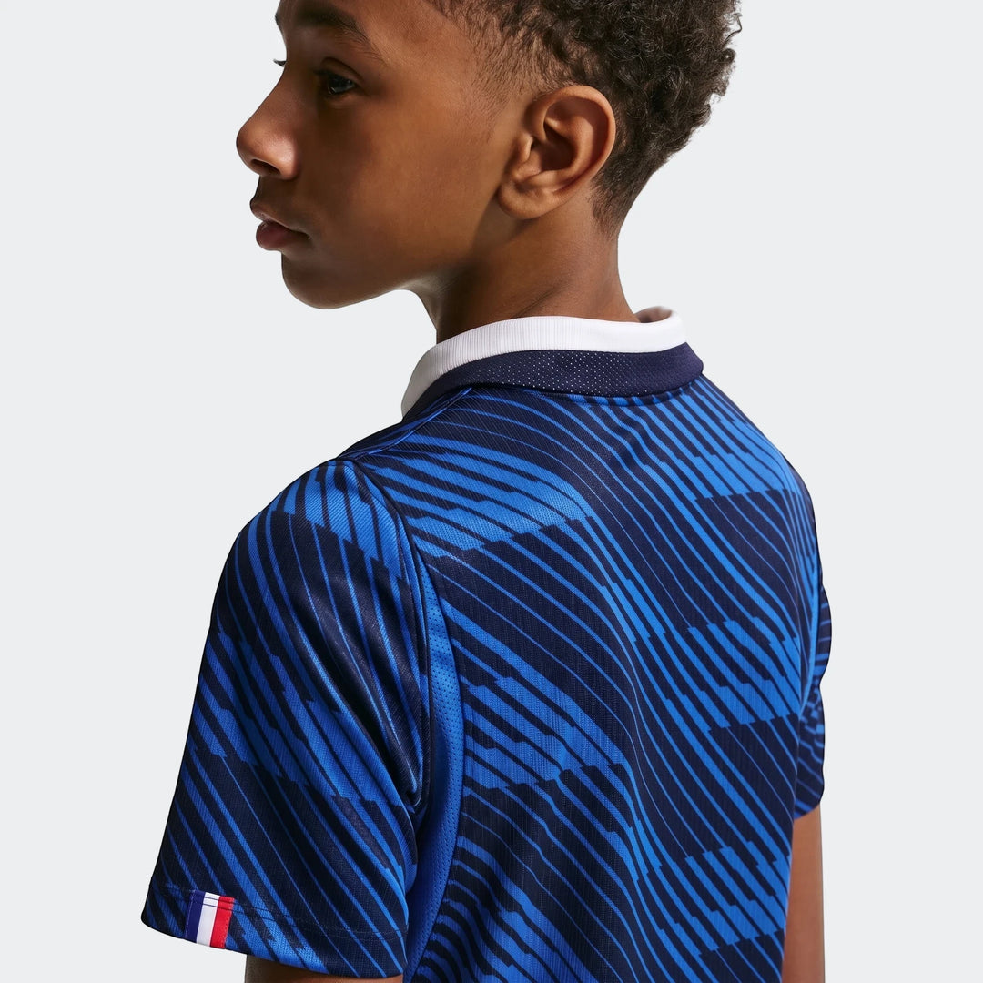 Young boy wearing a blue striped France National Team 2026 Stadium Home Nike Dri-Fit soccer jersey, side profile.