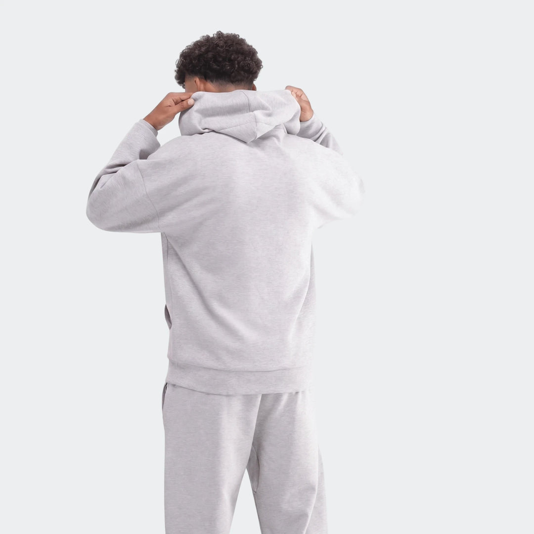 Light grey Future Icons 3-Bar Hoodie and matching sweatpants worn by a model, seen from the back, adjusting the hood.