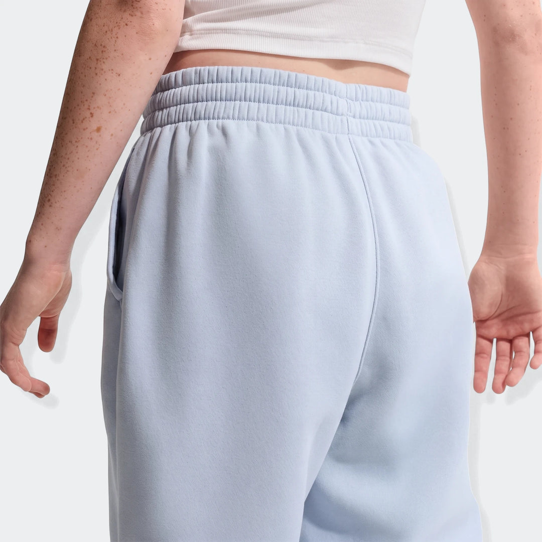 Back view of a person wearing light blue G Nsw Club fleece loose graphic pants, featuring an elasticated waist and pockets.