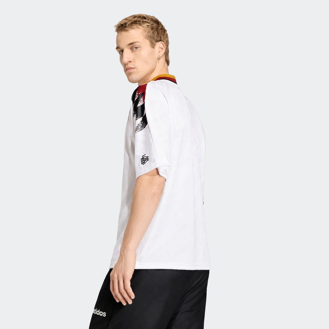 Male model wears a white Adidas Germany 1994 Retro Home Jersey, featuring iconic black, red, and yellow shoulder details.