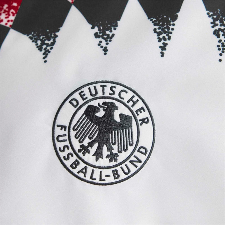 Close-up of the embroidered DFB logo on a white Germany 1994 Retro Track Top with black and red accents.