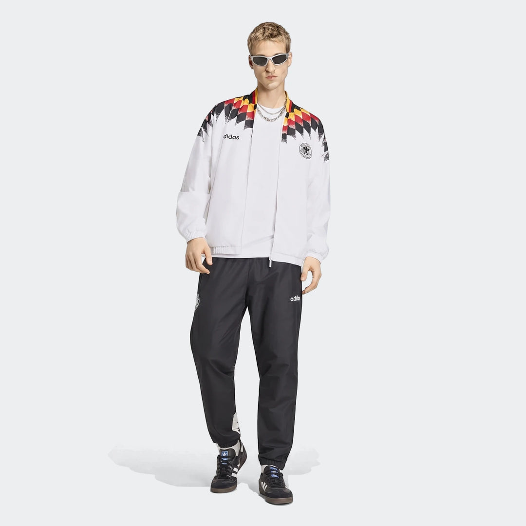 Male model wearing a white Adidas Germany 1994 Retro Track Top with black track pants and sneakers, full body view.