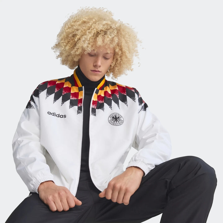 Male model wearing a white Adidas Germany 1994 Retro Track Top with black, red, and yellow checkerboard pattern.