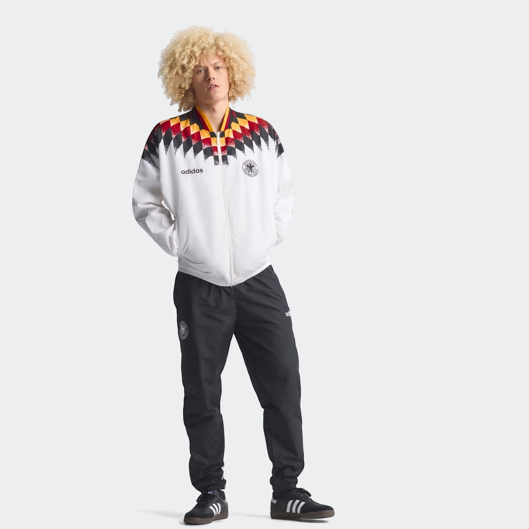 A male model showcases the Germany 1994 Retro Track Top, a white track jacket featuring a striking black, red, and yellow