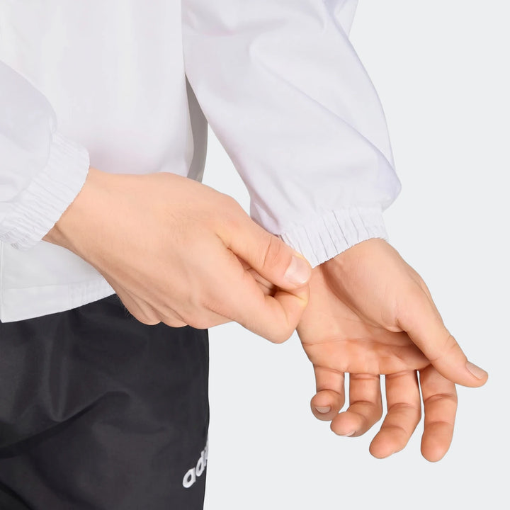 Close-up of a person's hands adjusting the white sleeve cuff of a Germany 1994 Retro Track Top, with black shorts visible.
