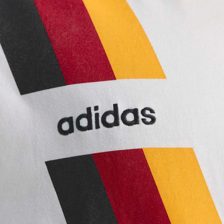 Close-up of a white Germany 1994 T-shirt featuring the black Adidas logo and black, red, and yellow flag stripes.