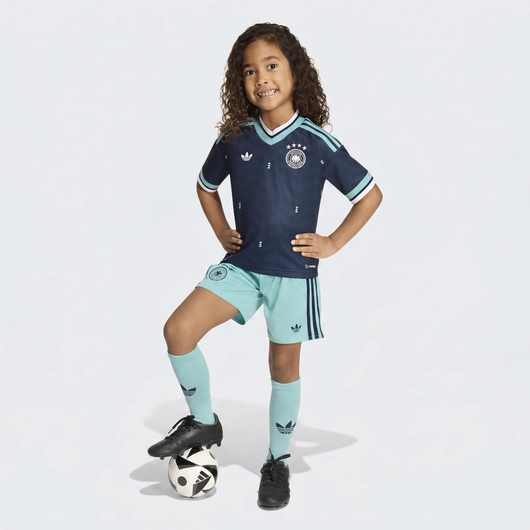 Young girl wearing Germany 25/26 Away Mini Kit in dark blue and light blue, featuring jersey, shorts, socks, and a soccer