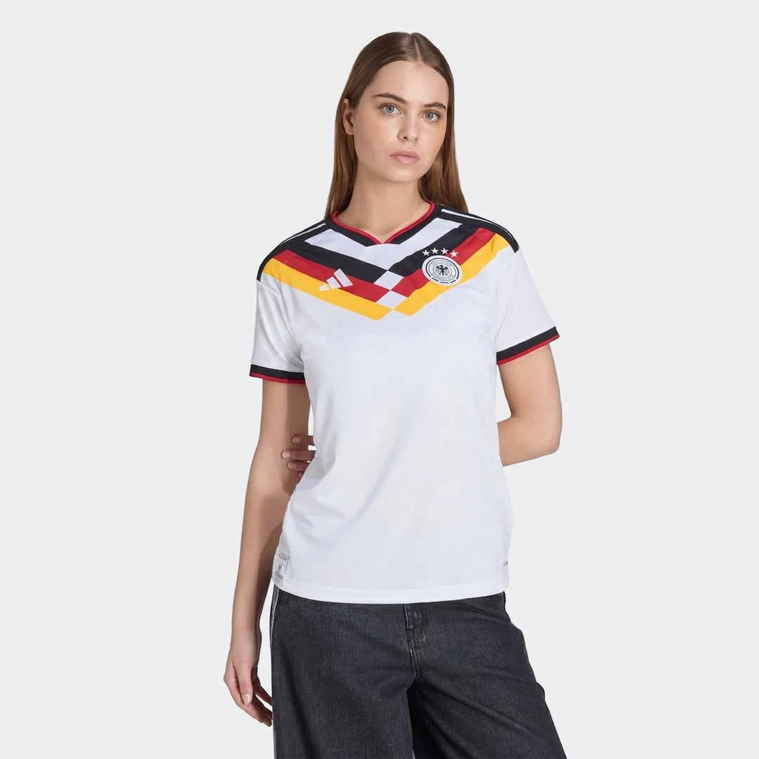 Woman wearing a white Germany 25/26 Home Jersey with red, yellow, and black details, featuring the national crest and Adidas