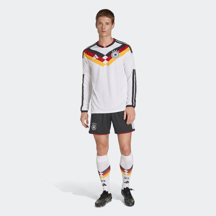Male model wearing a Germany 25/26 long sleeve home jersey, black shorts, and white socks.