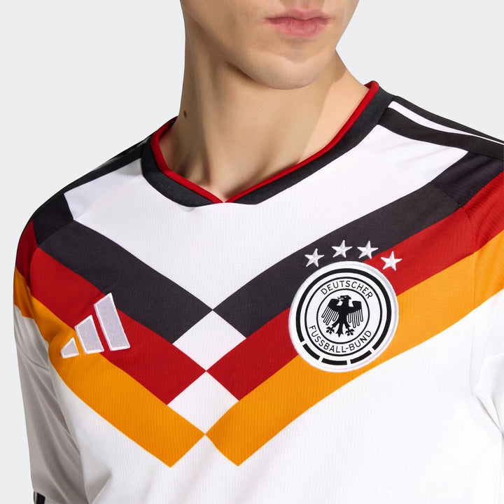 Close-up of a man wearing the white Germany 25/26 Long Sleeve Home Jersey with black, red, and yellow stripes, Adidas and