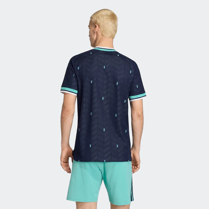 Male model wearing Germany 26 Away Authentic Jersey in navy blue, paired with light blue shorts, viewed from the rear.