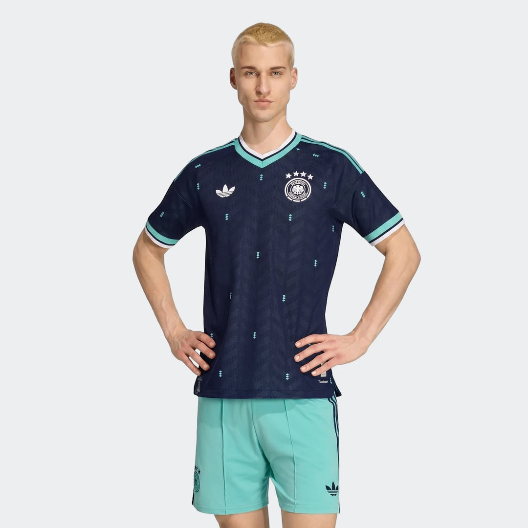 Germany 26 Away Authentic Jersey on a male model, full body shot, showing dark blue jersey with light blue accents and