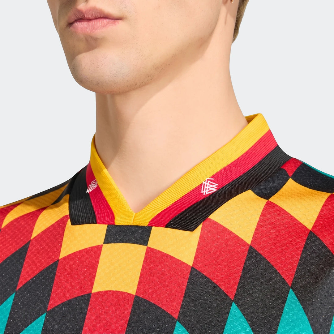 Close-up of a man wearing a Germany Away Jersey 1994, featuring a vibrant checkerboard pattern in red, yellow, black, and