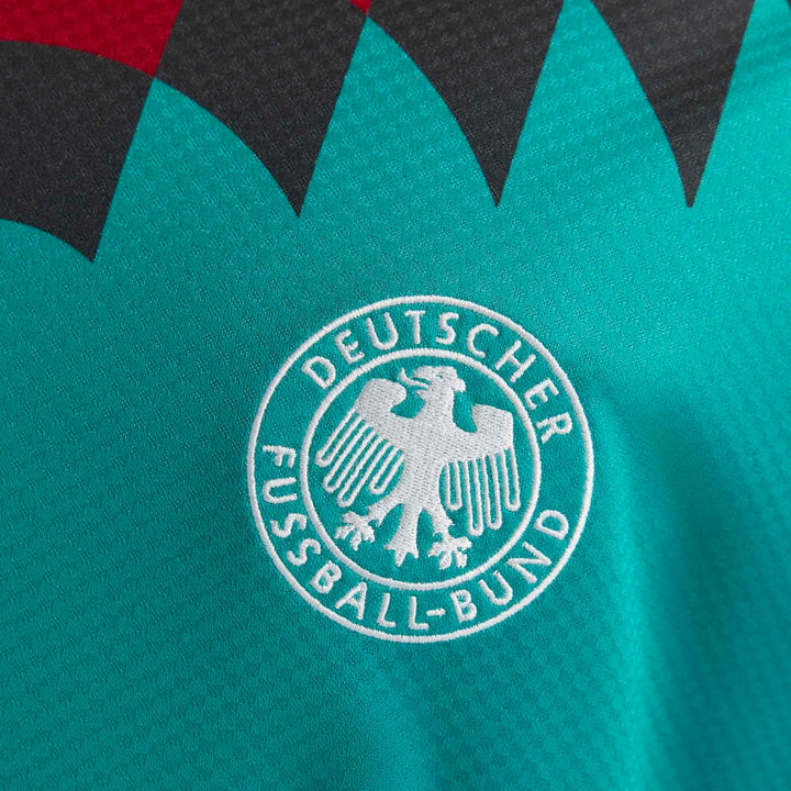 Close-up of a 1994 Germany away jersey in teal fabric with white embroidered Deutscher Fussball-Bund eagle logo.