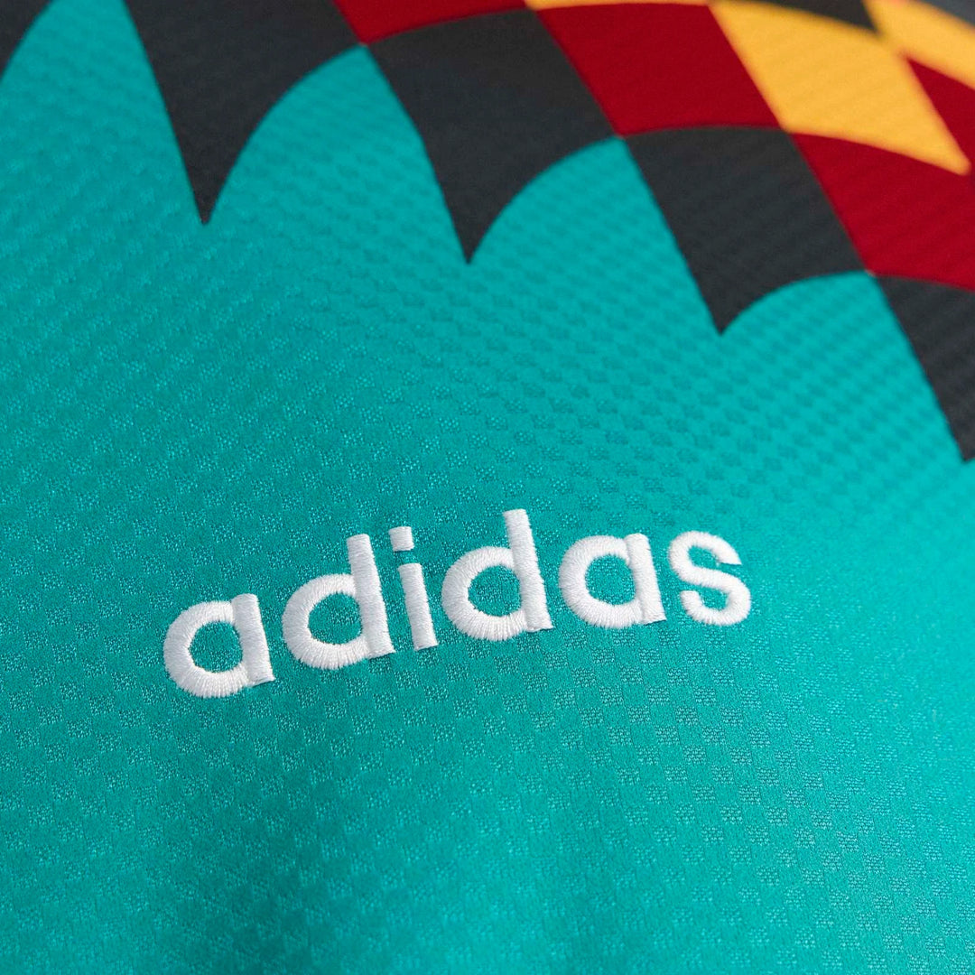 Close-up of the teal 1994 Germany Away Jersey fabric, showcasing the white embroidered Adidas logo and geometric pattern.