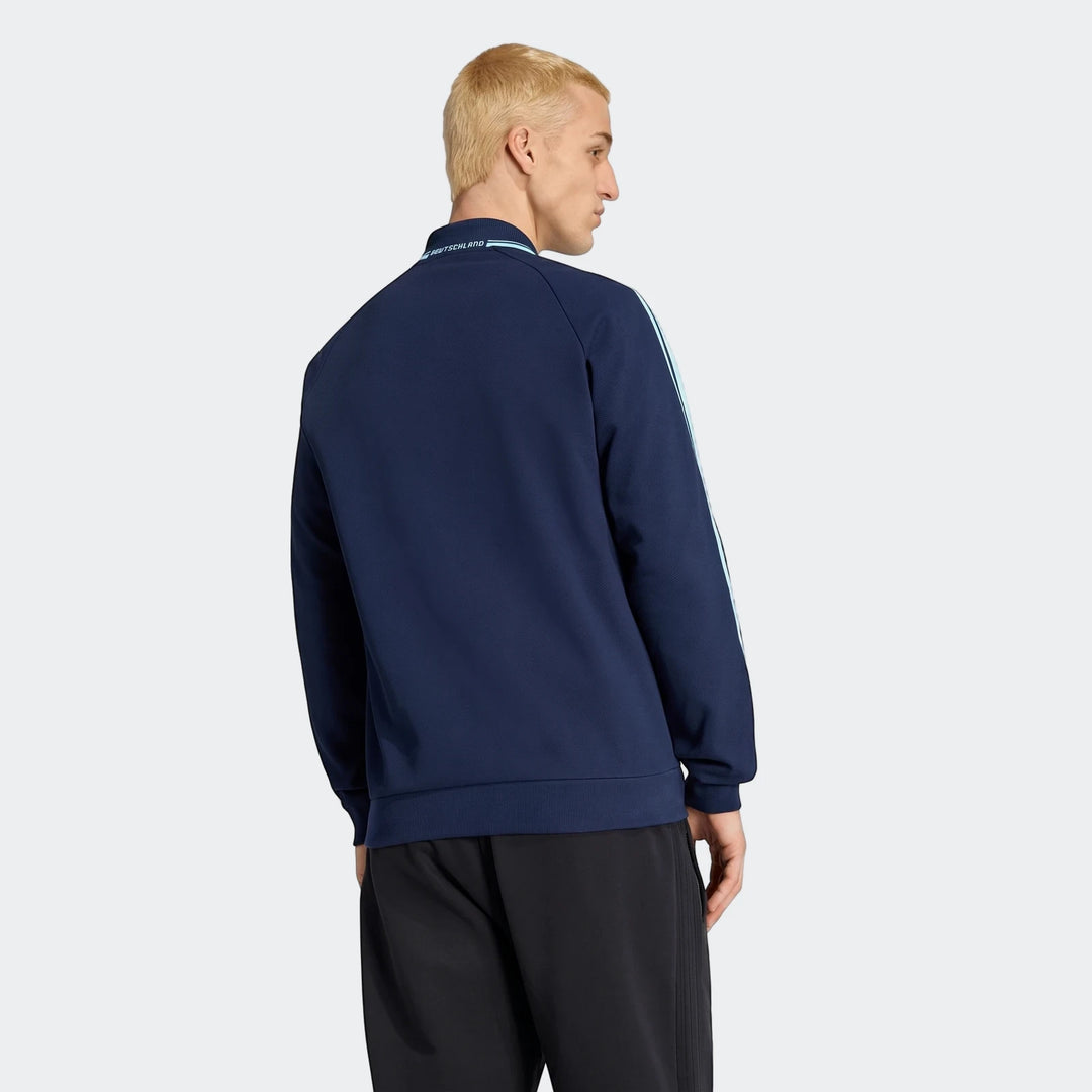 Male model wearing a navy Germany Away Originals Jacket, featuring light blue stripes and 'Deutschland' text on the collar,