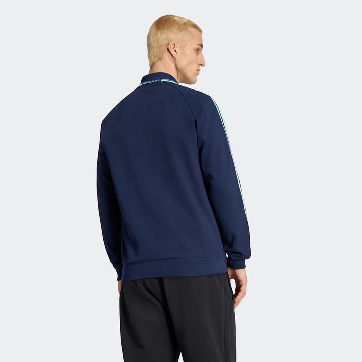 Male model wearing a navy Germany Away Originals Jacket, featuring light blue stripes and 'Deutschland' text on the collar,