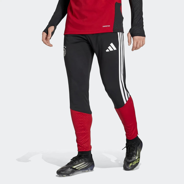 Black and red Adidas Germany training pants with white stripes, worn by a model, ideal for performance training.