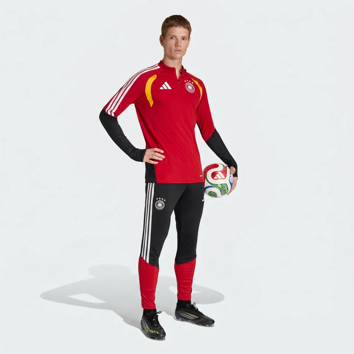 Male model wearing black and red Germany Training Pants and a matching long-sleeve top, holding a soccer ball.