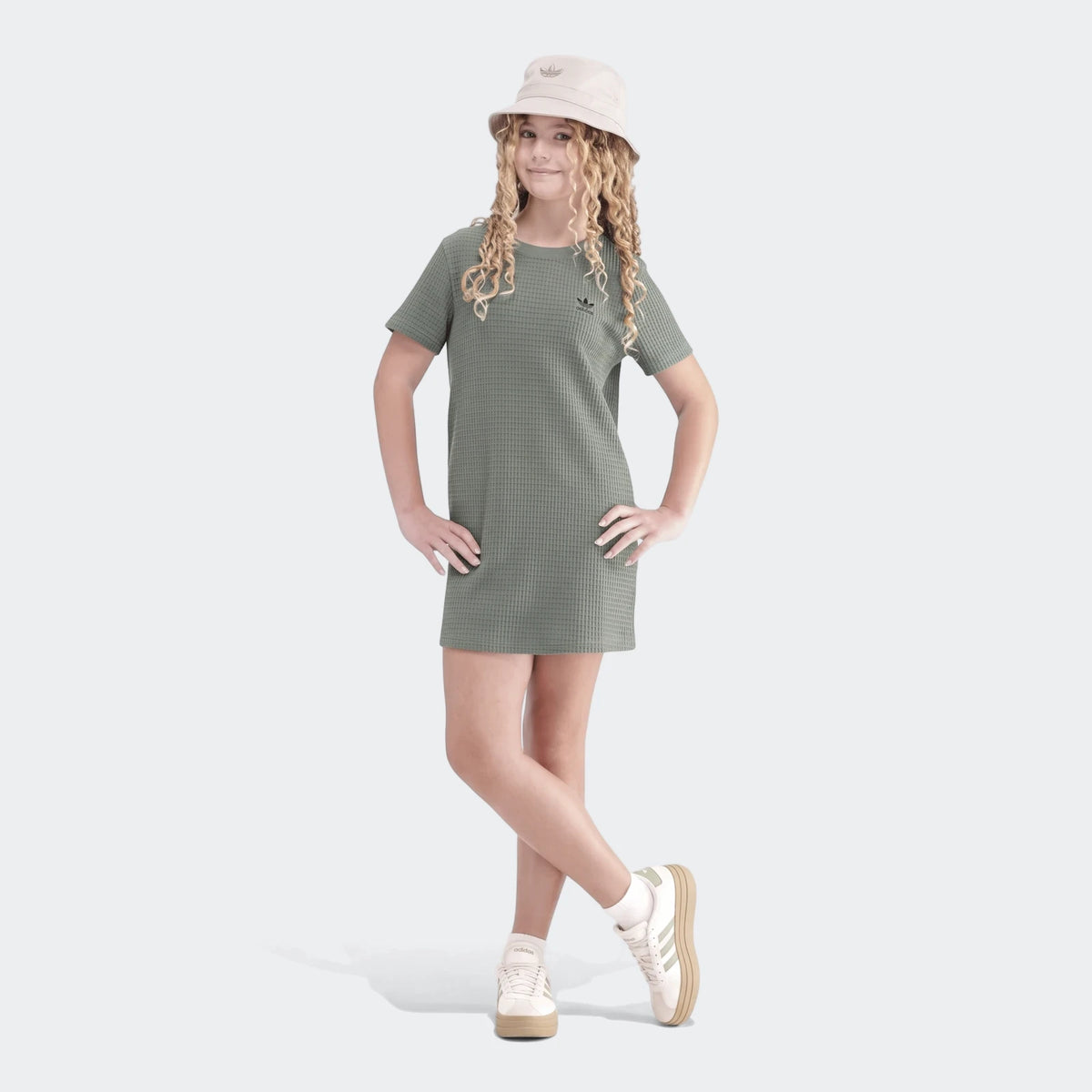 Young girl wearing a green Adidas short-sleeve waffle dress and a beige bucket hat, posing for a photo.