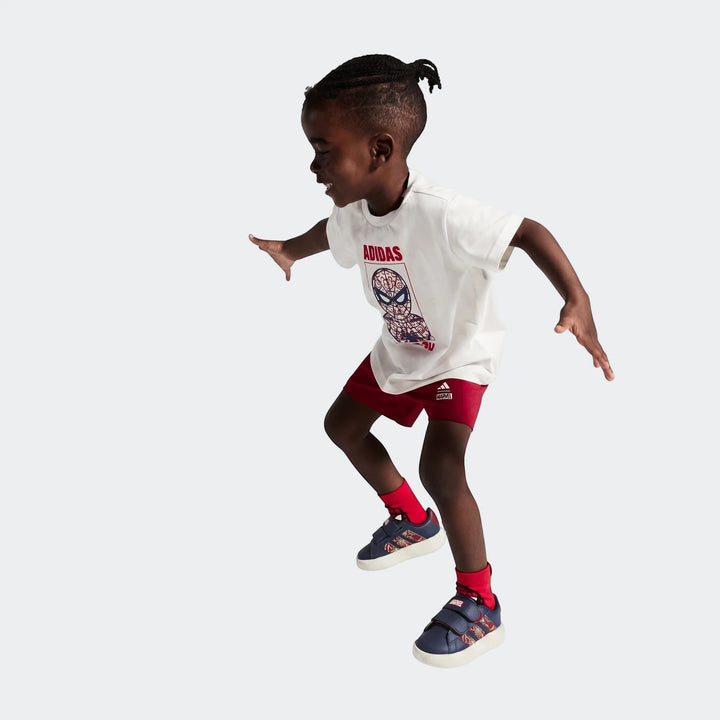 A young boy wearing a white Adidas Spider-Man t-shirt, red shorts, and navy Grand Court Spider-Man Cloudfoam Kids Shoes.