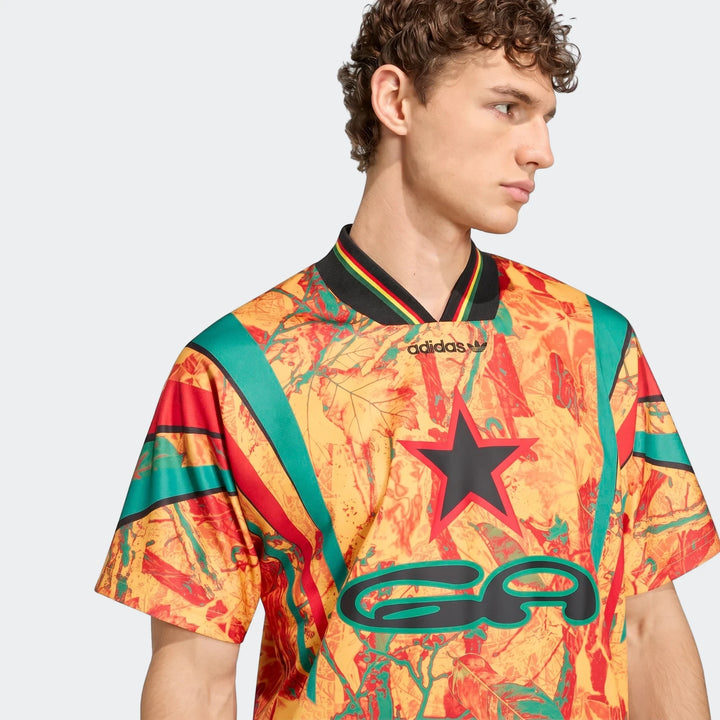 Close-up of a man wearing a colorful Adidas Graphic Football Jersey with a black star and 'ea' logo, featuring an abstract
