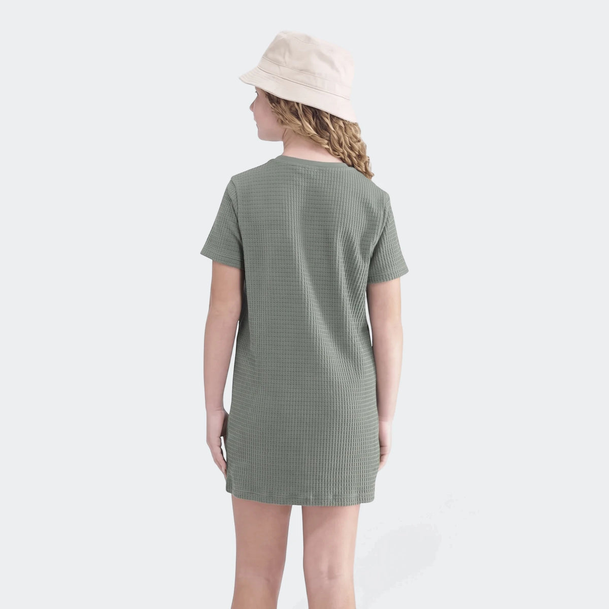 Young person from back wearing a green short-sleeve waffle dress and a beige bucket hat, isolated on white.