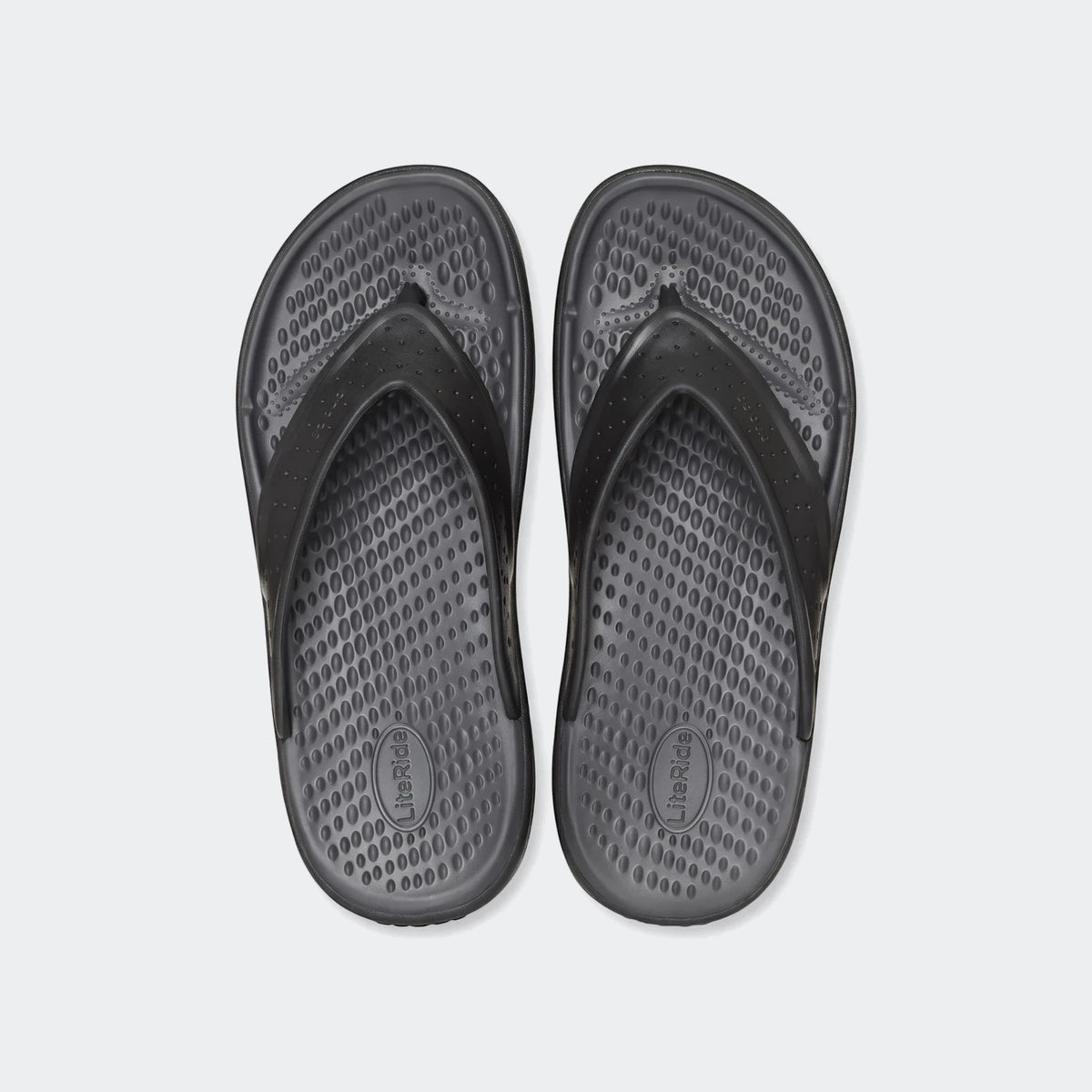Pair of black In Motion Lite Ride flip-flops with textured footbeds and perforated straps, laid flat on a white background.