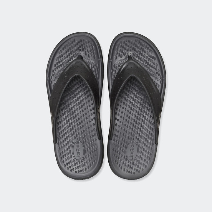 Pair of black In Motion Lite Ride flip-flops with textured footbeds and perforated straps, laid flat on a white background.