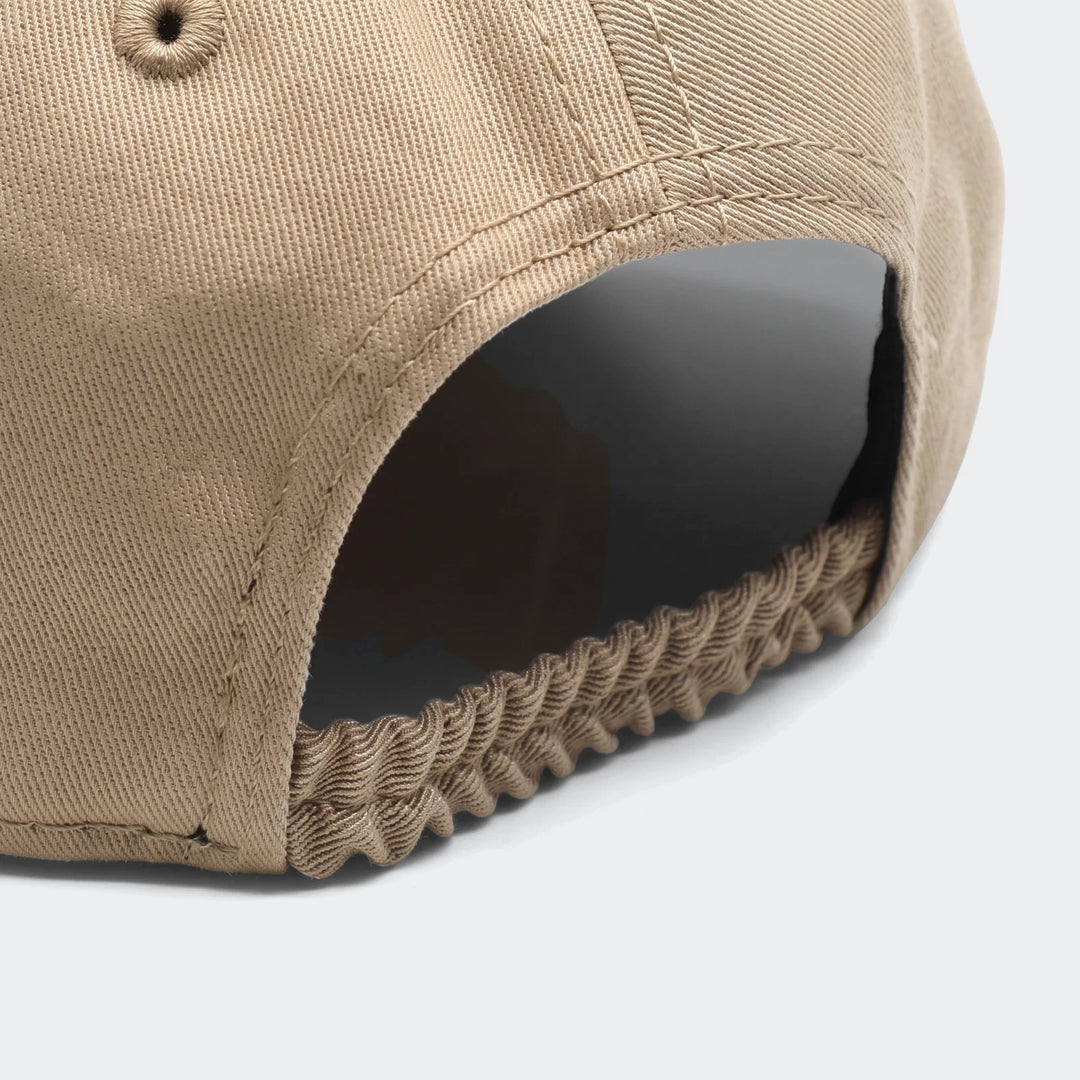 Close-up of a beige Infant League cap, featuring an elasticized back and visible textile weave.