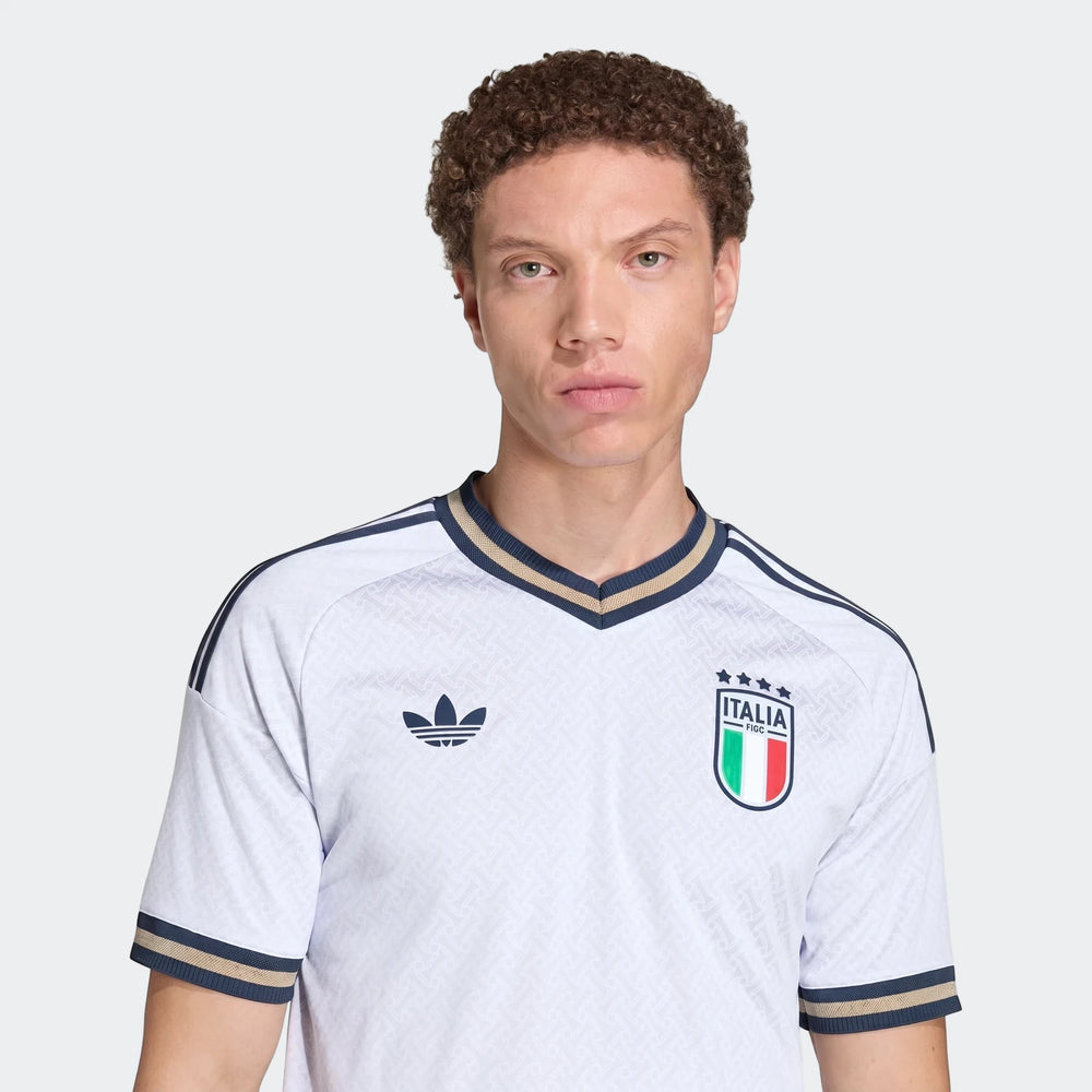 Male model wearing an Italy 25/26 Authentic Away Jersey in white, featuring navy and gold trim and national crest.