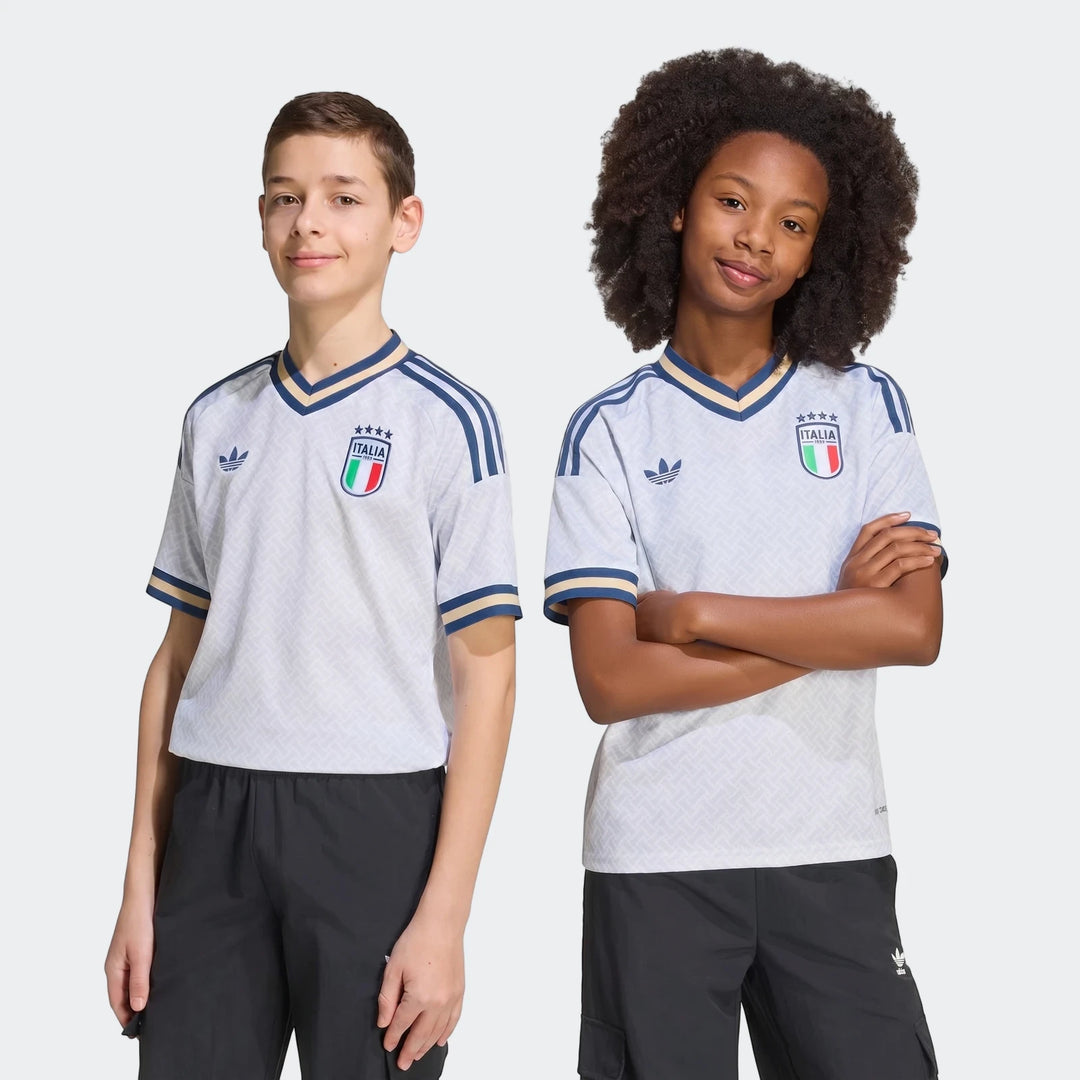 Two children model youth Italy 25/26 Away Jerseys, white with blue and gold details, in a studio shot.