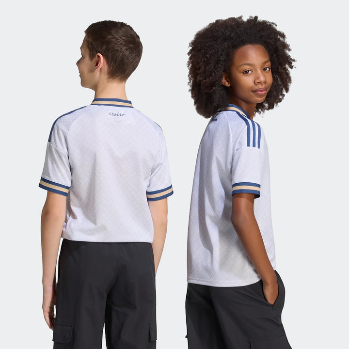 Two young boys modeling the Italy 25/26 Away Jersey Youth. The white short-sleeve jersey features blue and gold striped