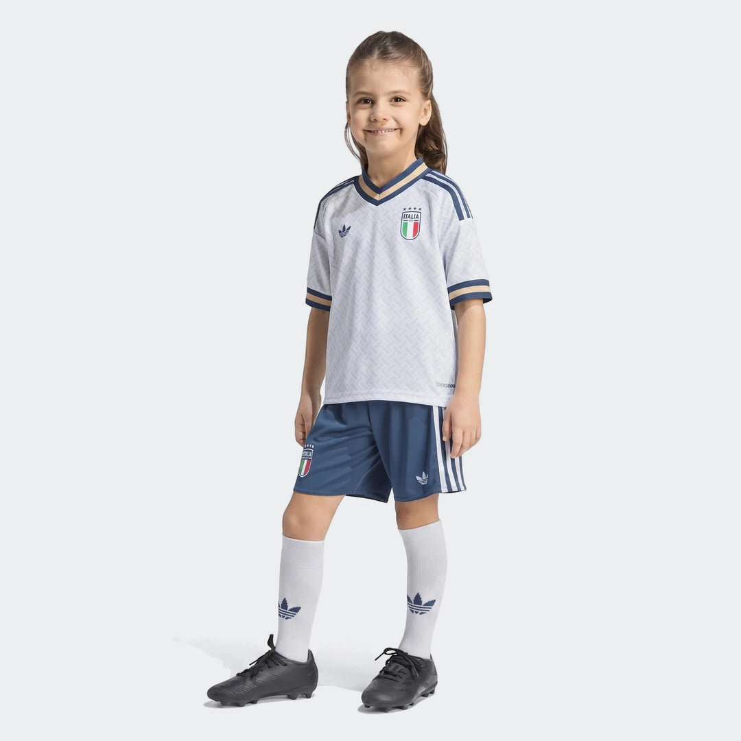 Young girl wearing the white and blue Italy 25/26 Away Mini Kit, complete with jersey, shorts, and socks.