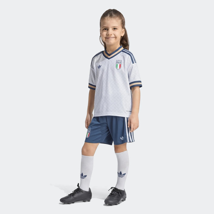 Young girl wearing the white and blue Italy 25/26 Away Mini Kit, complete with jersey, shorts, and socks.
