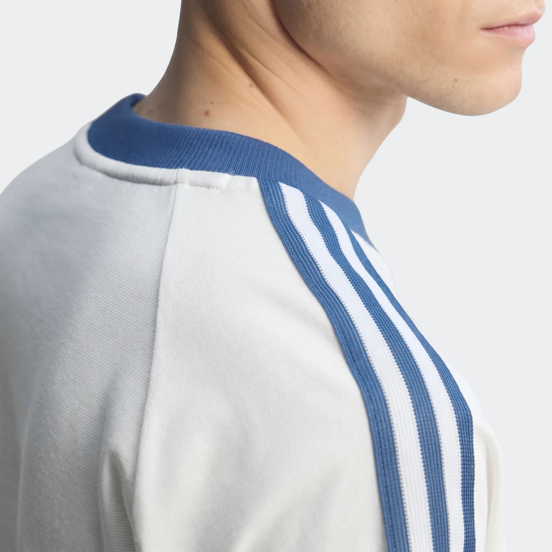 Close-up of a man wearing a white Italy Originals Graphic T-Shirt with blue stripes on the shoulder and a blue collar.