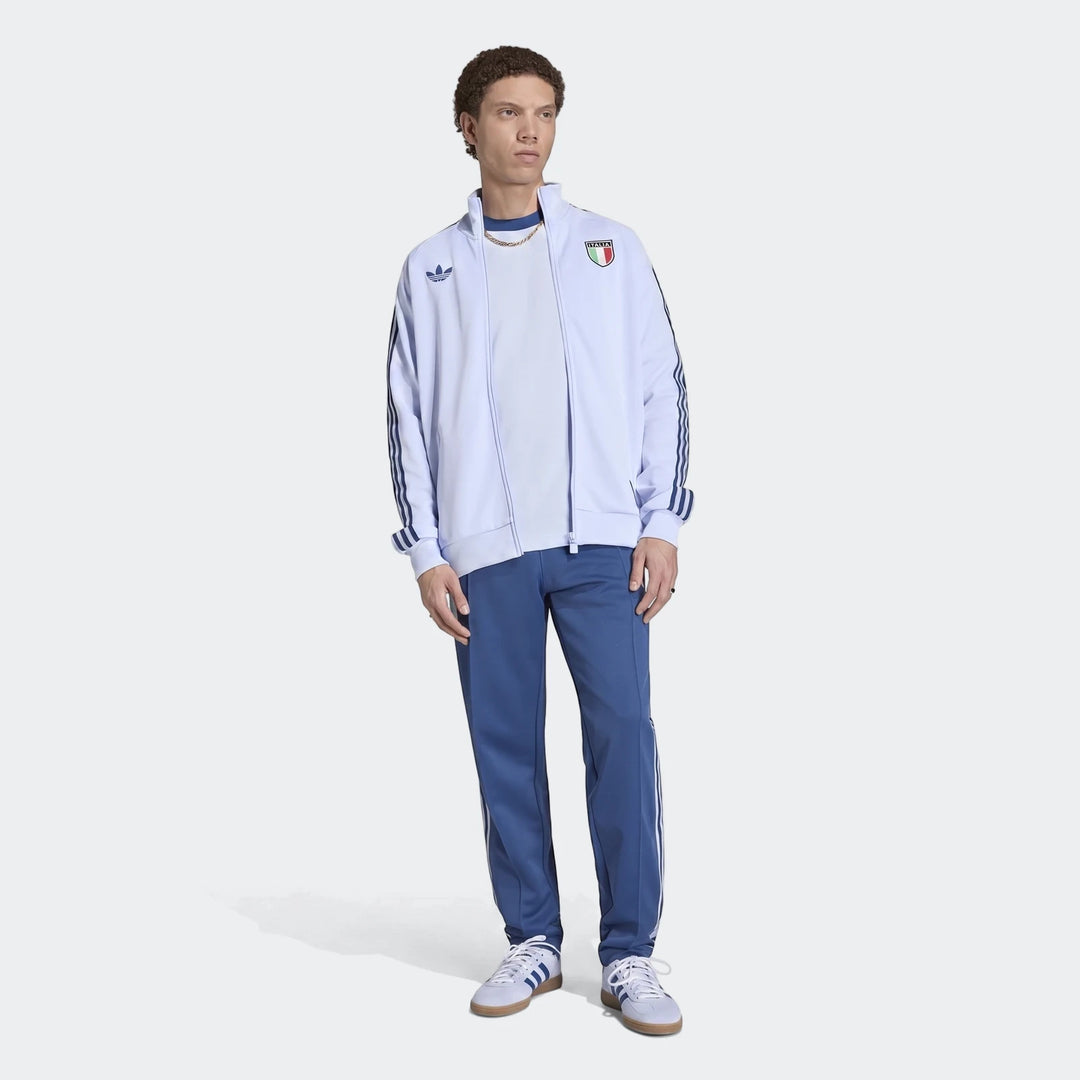 Italy Originals Track Top, male model in full body shot wearing light blue Adidas track jacket, blue track pants, and white
