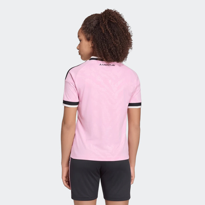 Youth wearing pink Juventus 26/27 Away Jersey, seen from the back, featuring a subtle pattern and black detailing.